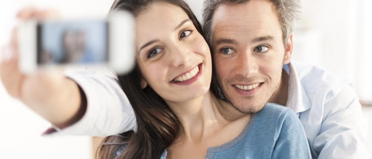 Ein Paar nimmt ein gemeinsames Selfie auf, während es auf einem Sofa sitzt.