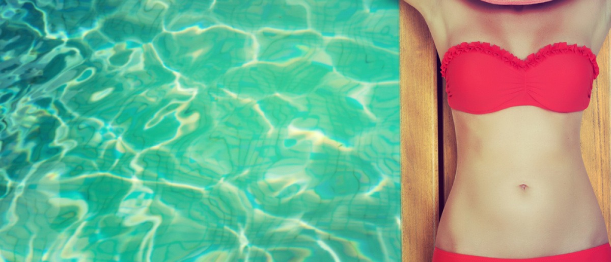 Eine Frau liegt auf einer Matte im Wasser, den Sonnenhut über den Kopf gezogen