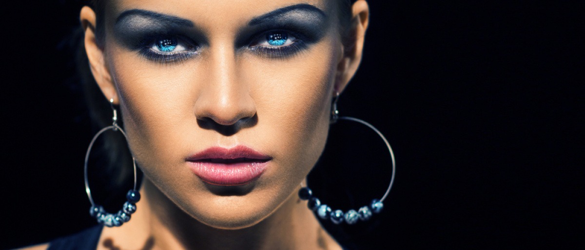 Eine Frau hat mit blauem Lidschatten Smokey Eyes geschminkt