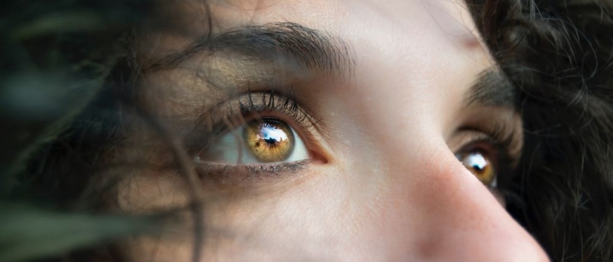 Eine Frau mit Locken hat leuchtende bernsteinfarbene Augen