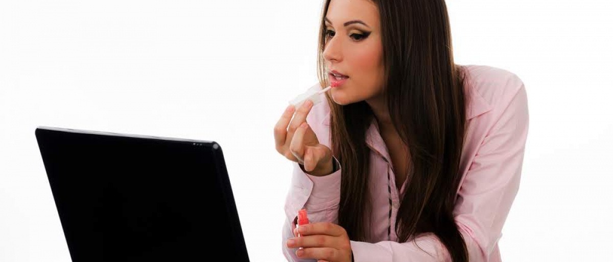Frau im Büro die sich vor dem PC schminkt