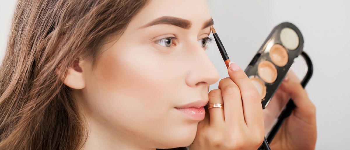 Das Gesicht einer Frau wird mit Camouflage Make-up geschminkt
