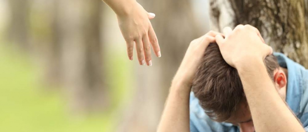 Eine Hand reicht zu einem depressiven Partner
