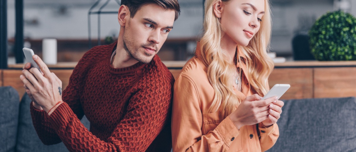 Ein junges Paar sitzt auf der Couch mit dem Handy in ihrer Handy