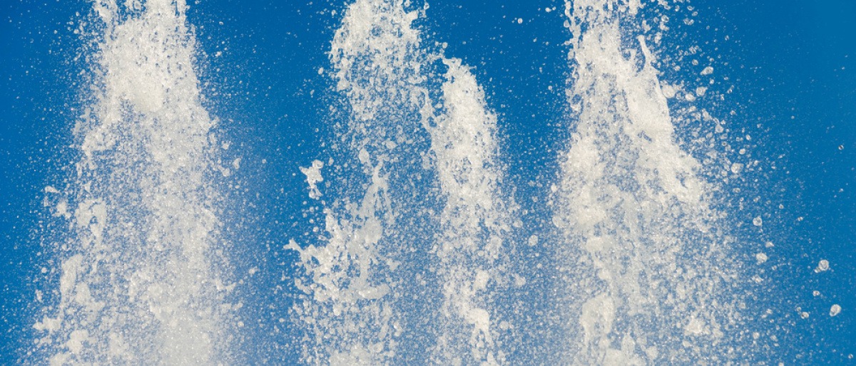 Weiße Fontänen spritzen vor einem blauen Hintergrund