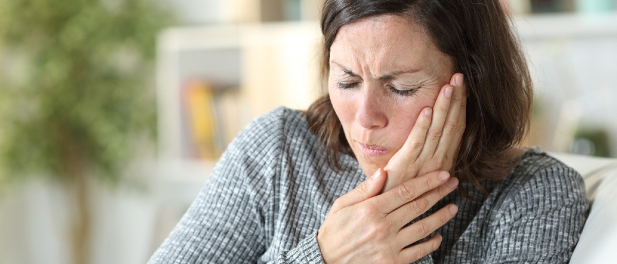 Eine Frau hat Schmerzen wegen einer Erkrankung im Mund