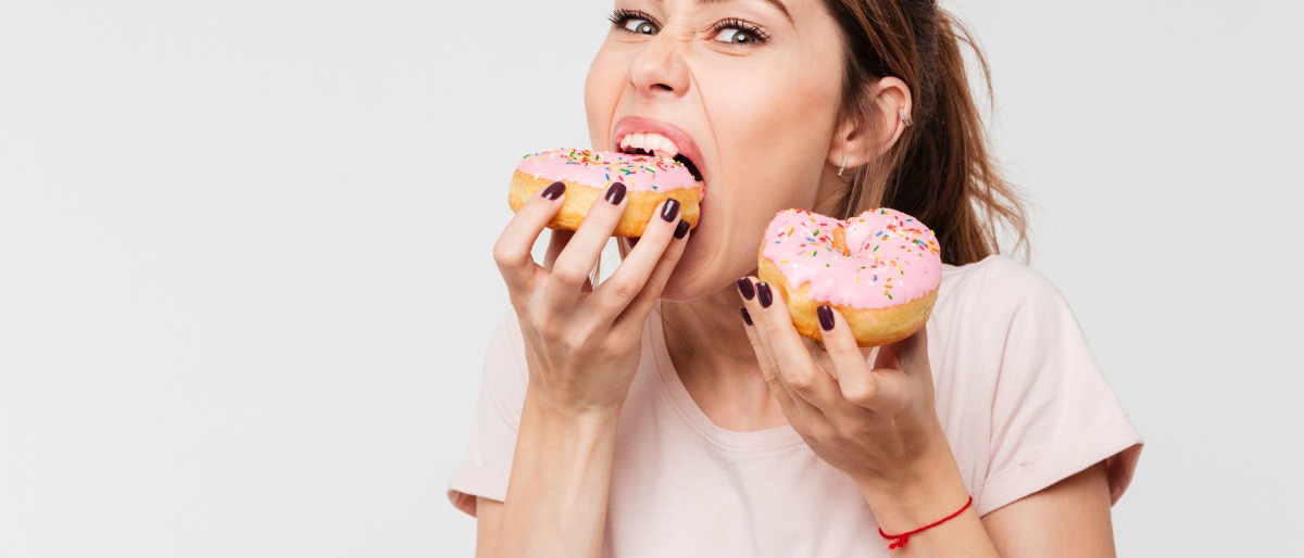 Frau isst aus Stress Doughnuts.