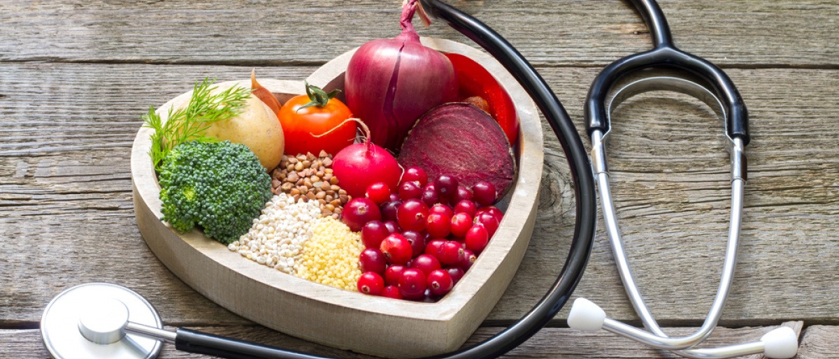 Essen zum Cholesterin senken liegt in einer Herzform, daneben ein Stetoskop