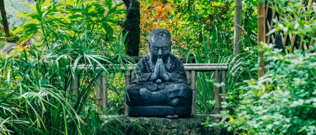 In einem Feng Shui Garten befindet sich eine Buddhastatue aus Stein