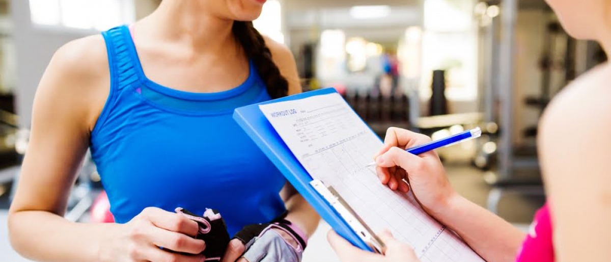 Eine Fitnesstrainerin mit einer Checkliste