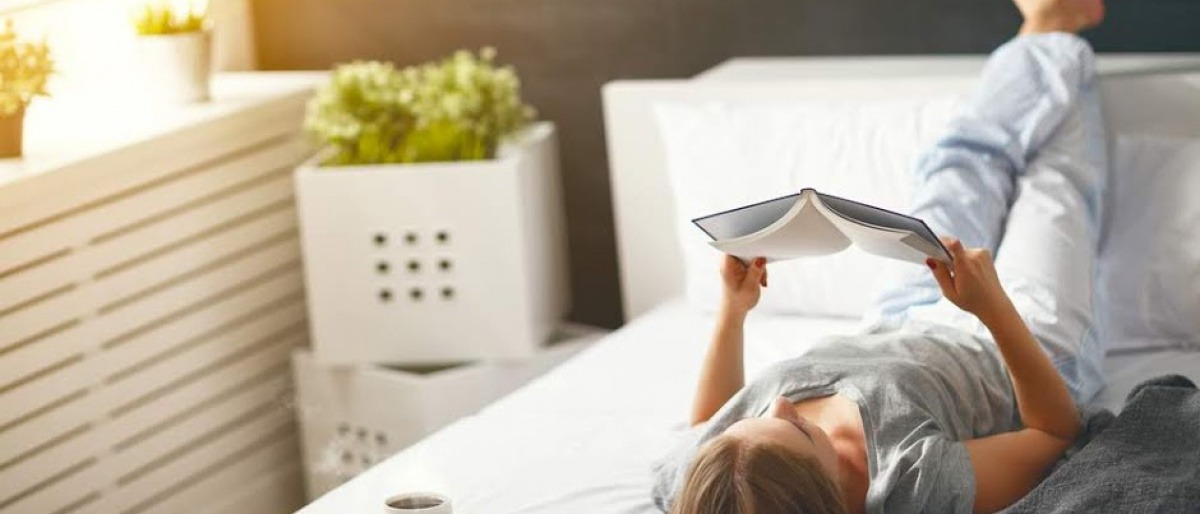 Eine Frau liegt im Bett und liest ein Buch