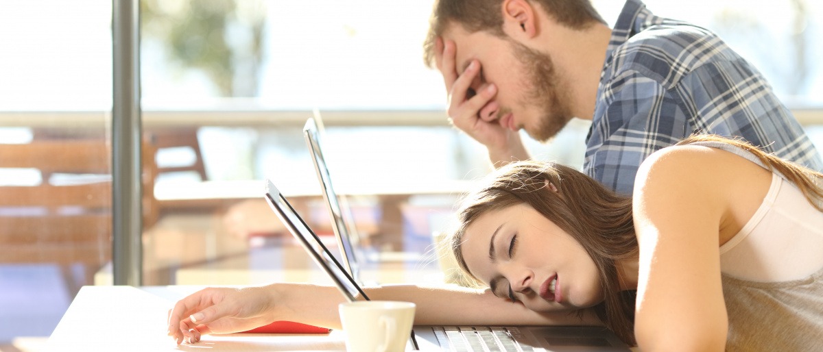 Eine Frau und ein Mann sind müde vom Arbeiten am Laptop