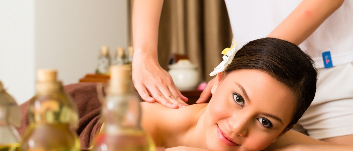 Eine Frau liegt bei einer Lomi Lomi Massage, Öle stehen daneben