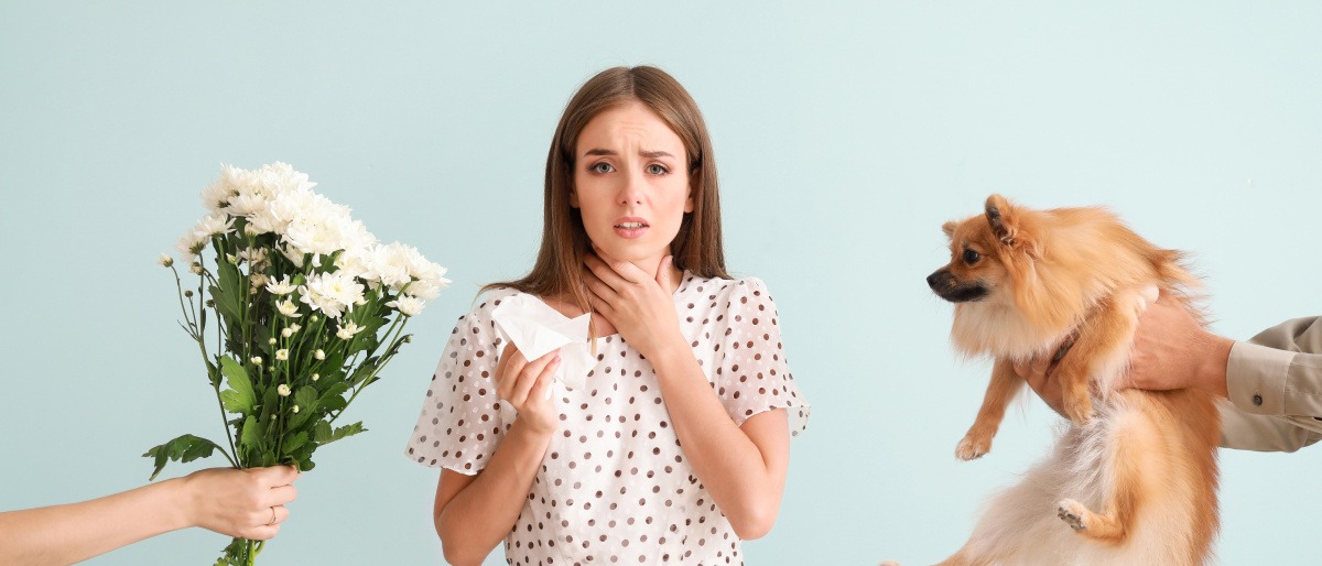 Einer Frau mit Allergie werden ein Blumenstrauß und ein Hund gereicht
