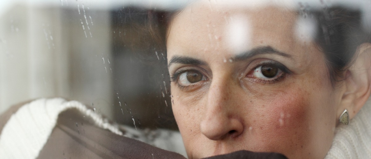Eine Frau sieht traurig und nachdenklich aus dem Fenster