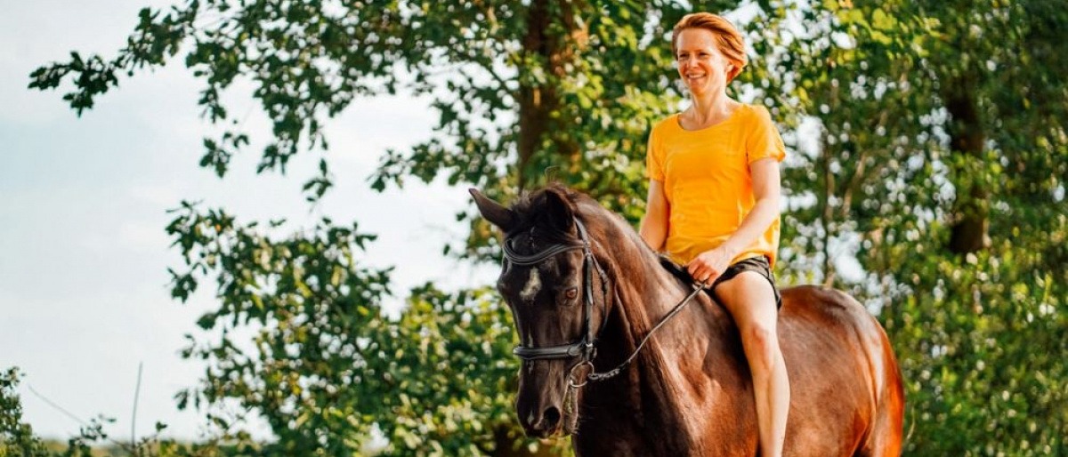 Eine Frau reitet ohne Sattel auf einem schwarzen Pferd