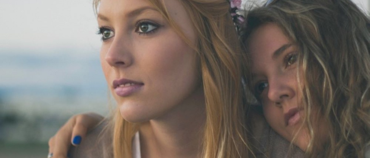 Zwei Frauen umarmen sich und blicken bewusst drein