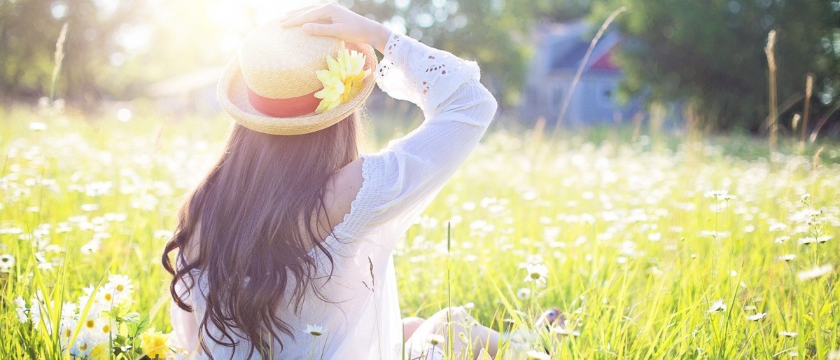 Frau sitzt im Gras und genießt die Frühlingssonne