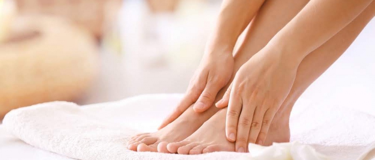 Eine Frau hält ihre Füße ohne Nagelpilz
