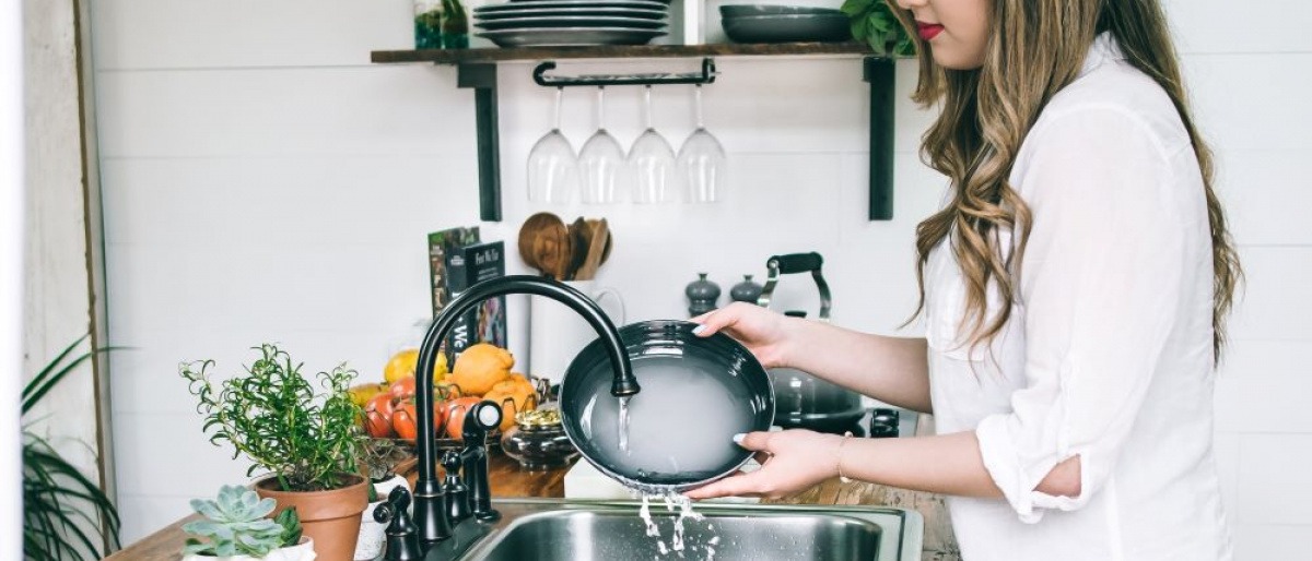 Eine Frau wäscht Geschirr mit selbst gemachtem Spülmittel