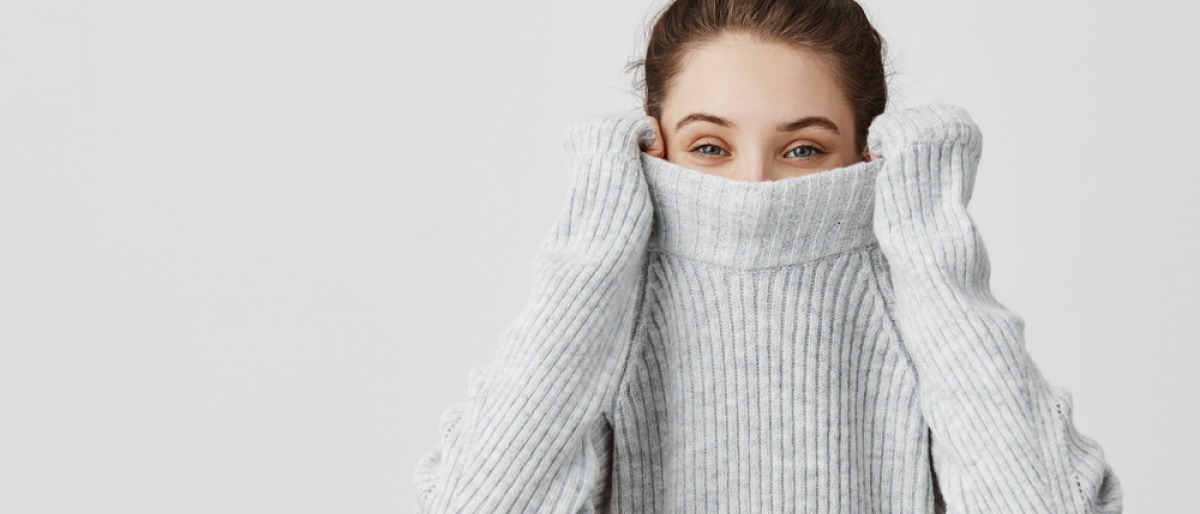 Frau versteckt ihr Gesicht mit Pigmentflecken im Pullover