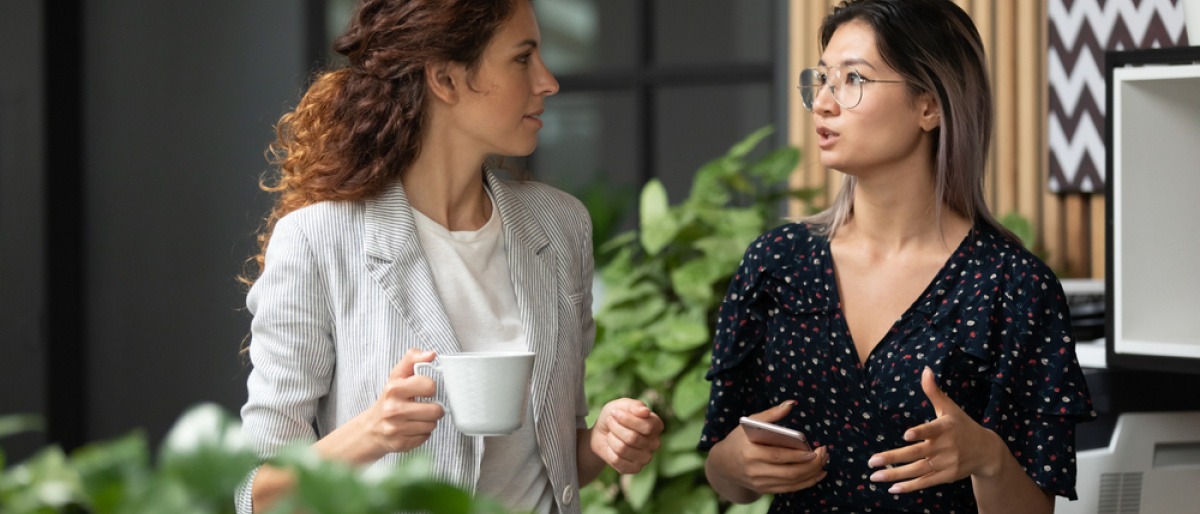 Zwei Frauen halten Smalltalk in der Kantine ihrer Arbeitsstelle.