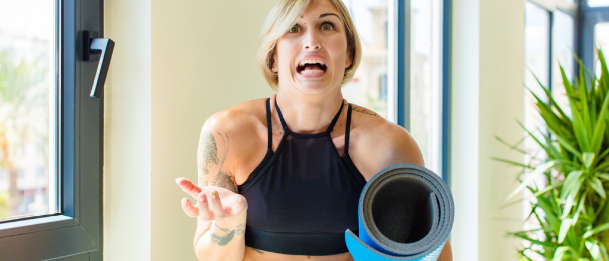 Verzweifelte oder unschlüssige Frau mit Yoga-Matte unter dem Arm.