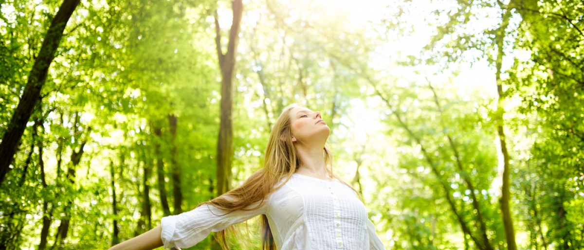 Eine Frau steht im Wald mit guter Laune im Frühling