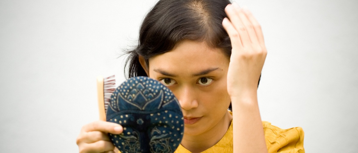 Frau untersucht Haare vor Handspiegel