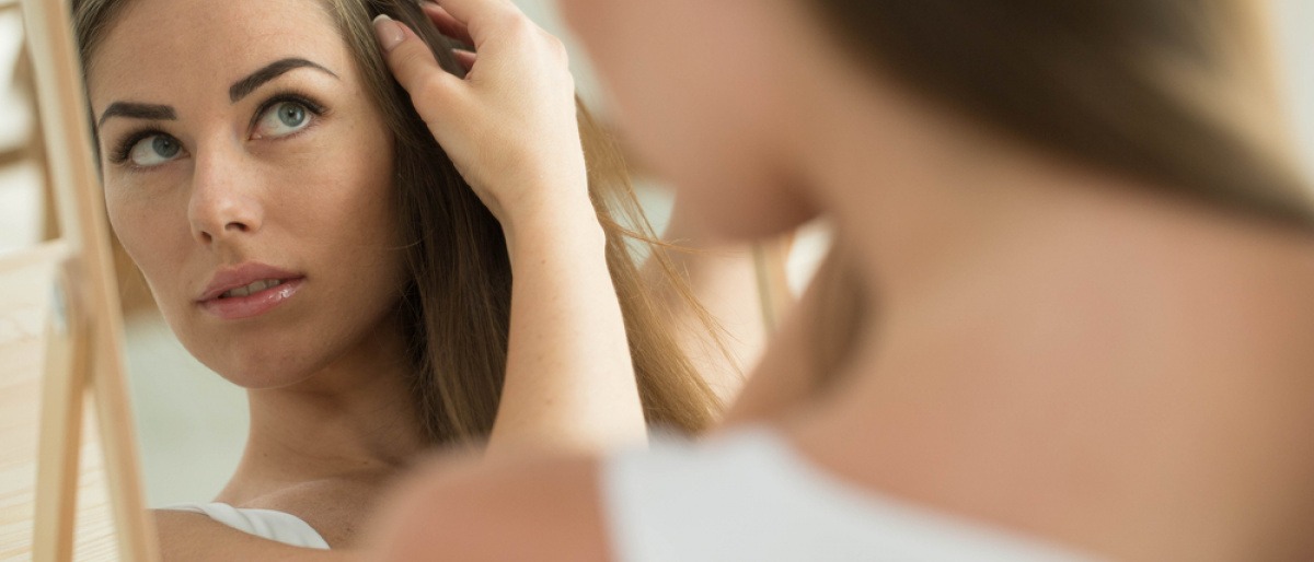 Eine Frau betrachtet ihren Haarausfall und ihre Kopfhaut