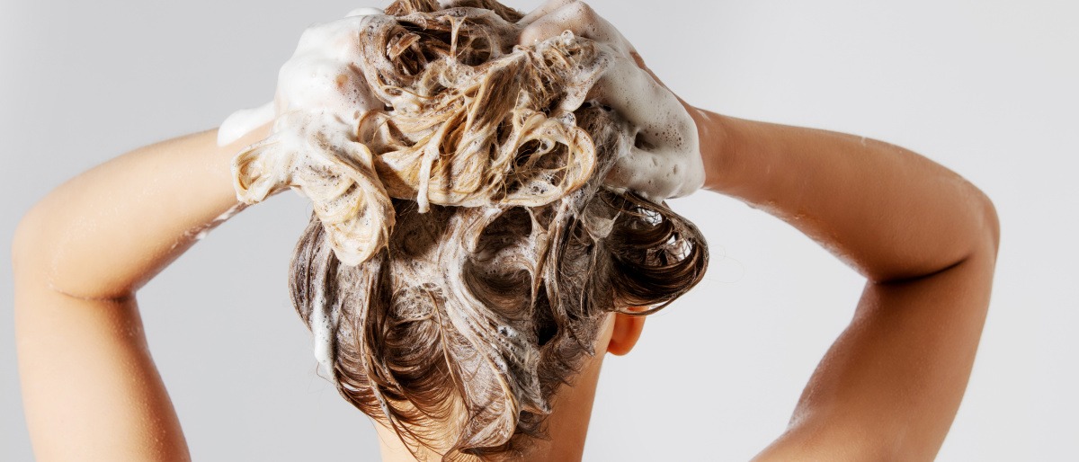 Eine Frau wäscht mit Silbershampoo ihre Haare gegen Gelbstich