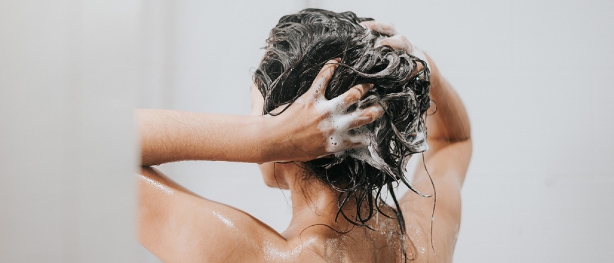 Frau beim Haarewaschen mit Haarpeeling