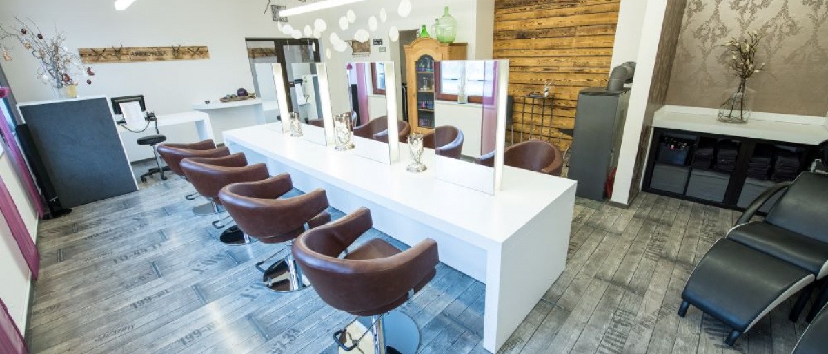 Vor einem weißen Friseurwaschbecken steht ein schwarzer Stuhl