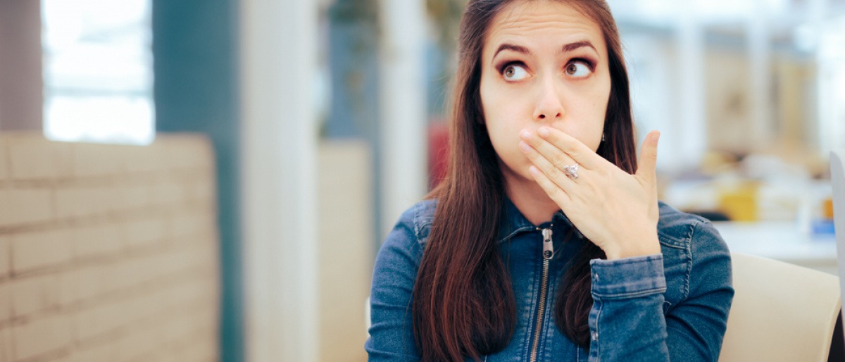 Frau hält Hand vor Mund wegen häufigen Aufstoßen nach dem Essen