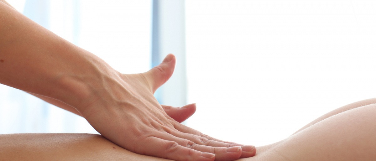 Eine Hand massiert bei einer erotischen Massage einen nackten Rücken