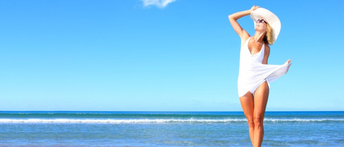 Frau am Strand will Haut auf Sonne vorbereiten