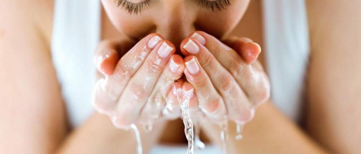 Frau reinigt ihr Gesicht, indem sie es wäscht