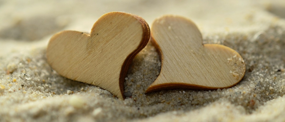 Herzen aus Holz liegen im Sand
