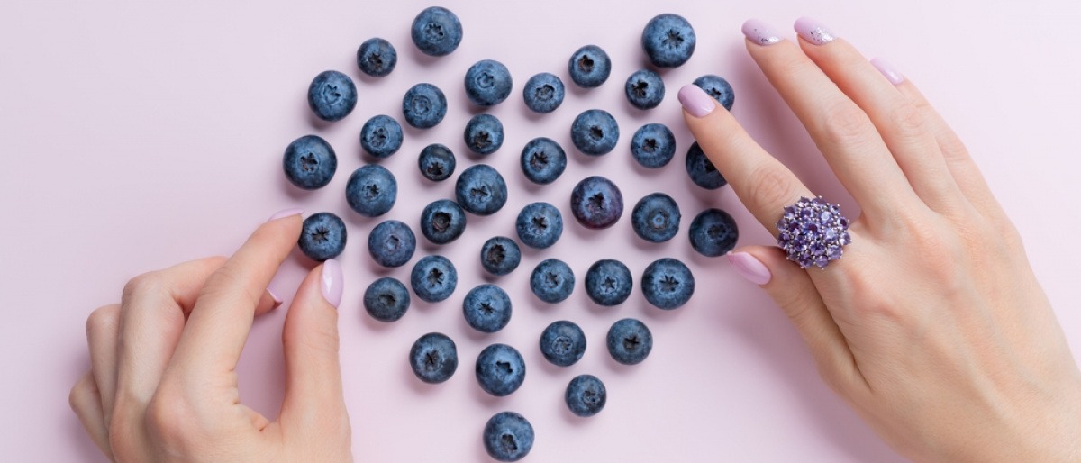Frau formt Herz aus Heidelbeeren mit der Hand.