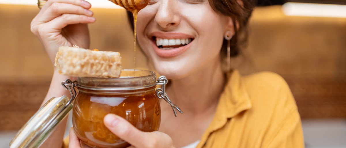 Frau mit Honig vor dem Gesicht