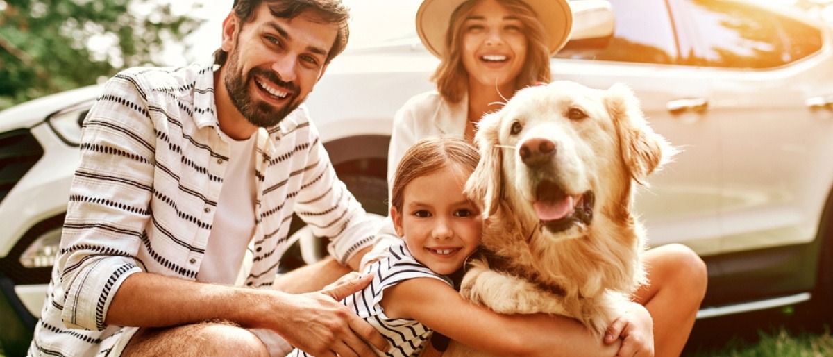 Hund mit Familie vor Auto