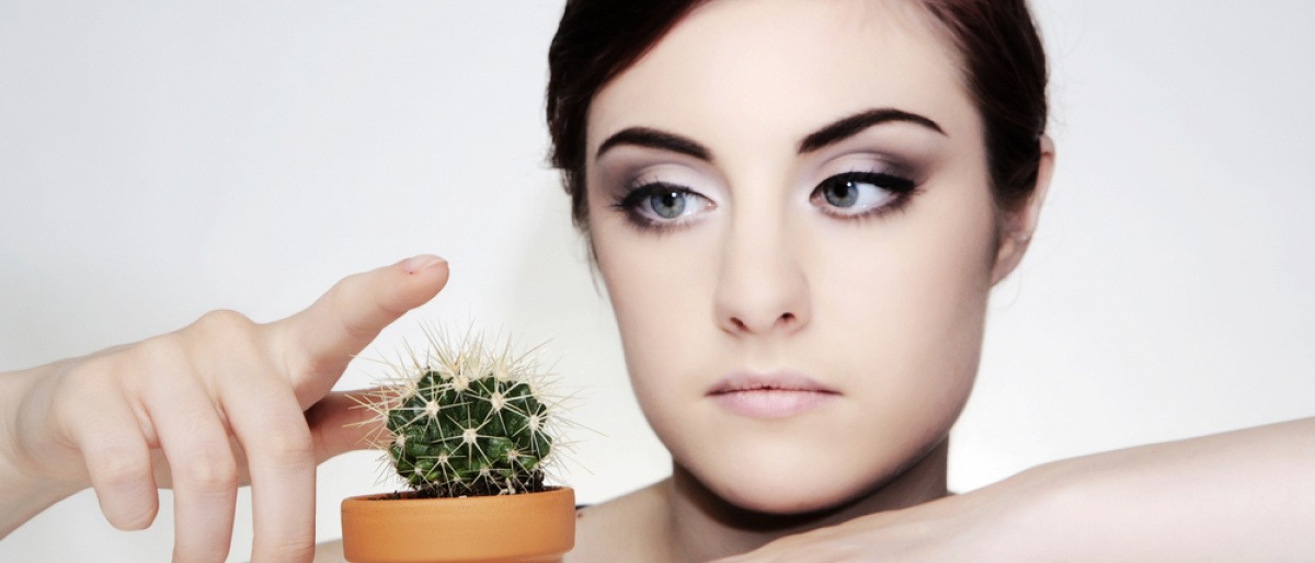 Eine Frau mit hypersensibler Haut greift auf einen Kaktus