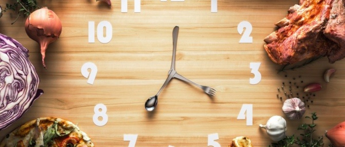 Auf einer Uhr sind Nahrungsmittel als Symbol für Intervallfasten