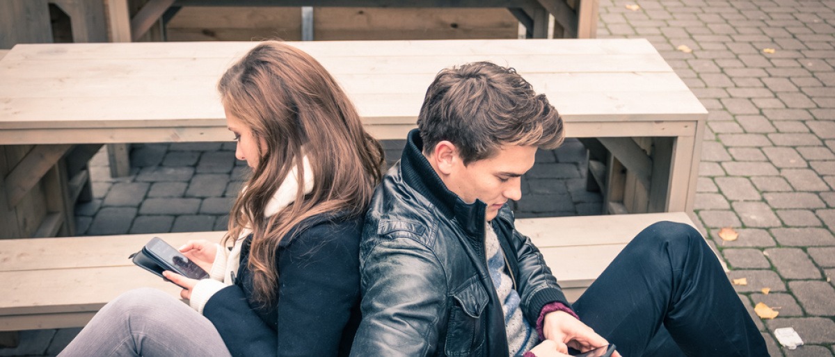 Keine Gemeinsamkeiten - Beziehung auf Abruf? Paar sitzt Rücken an Rücken auf dem Sofa, beide beschäftigen sich mit ihrem Smartphone.