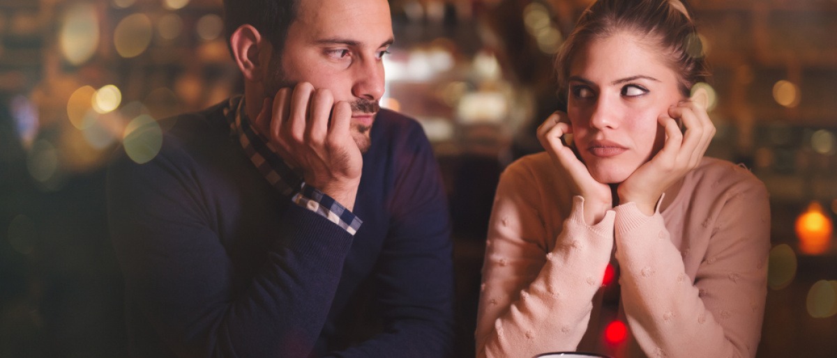 Eine Frau und ein Mann in einer Bar schauen sich gelangweilt an