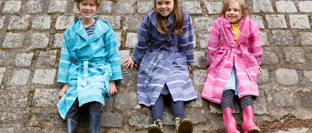 drei Kinder in bunten Bademänteln