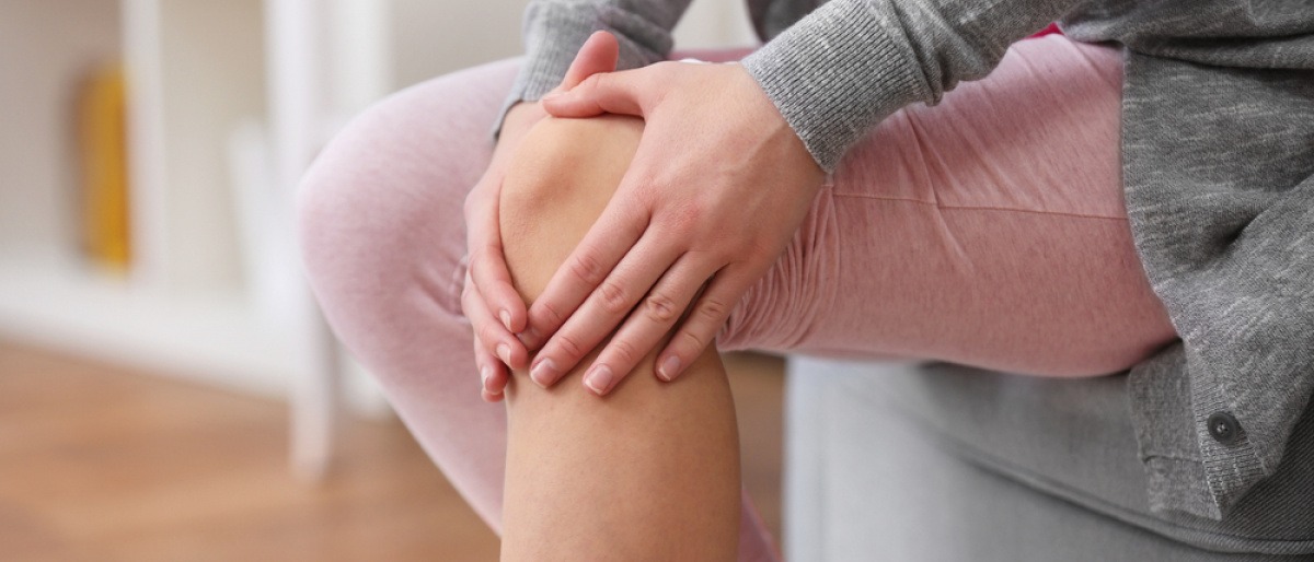 Frau greift sich ans Knie