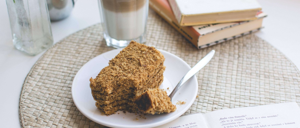 Neben einem Kuchen mit Nüssen steht eine Tasse Kaffee