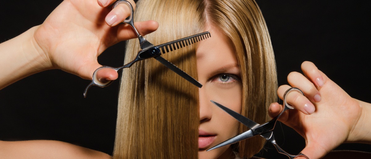 Eine Frau schneidet ihre langen Haare mit einer Schere mittellang