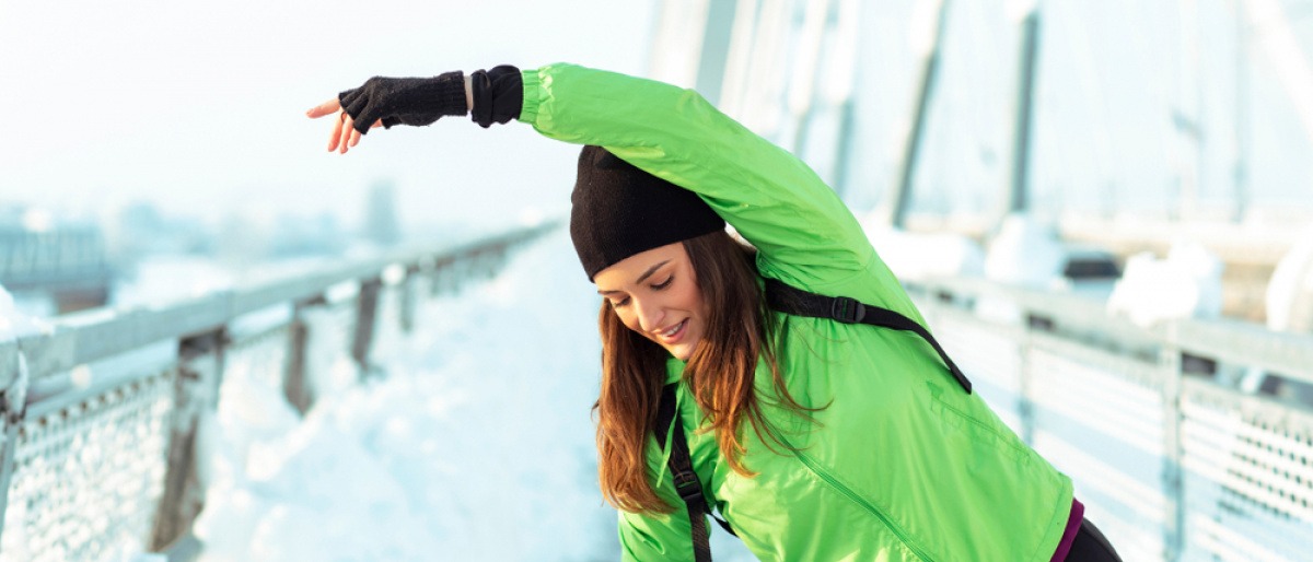 Junge Frau im Winter beim Dehnen.